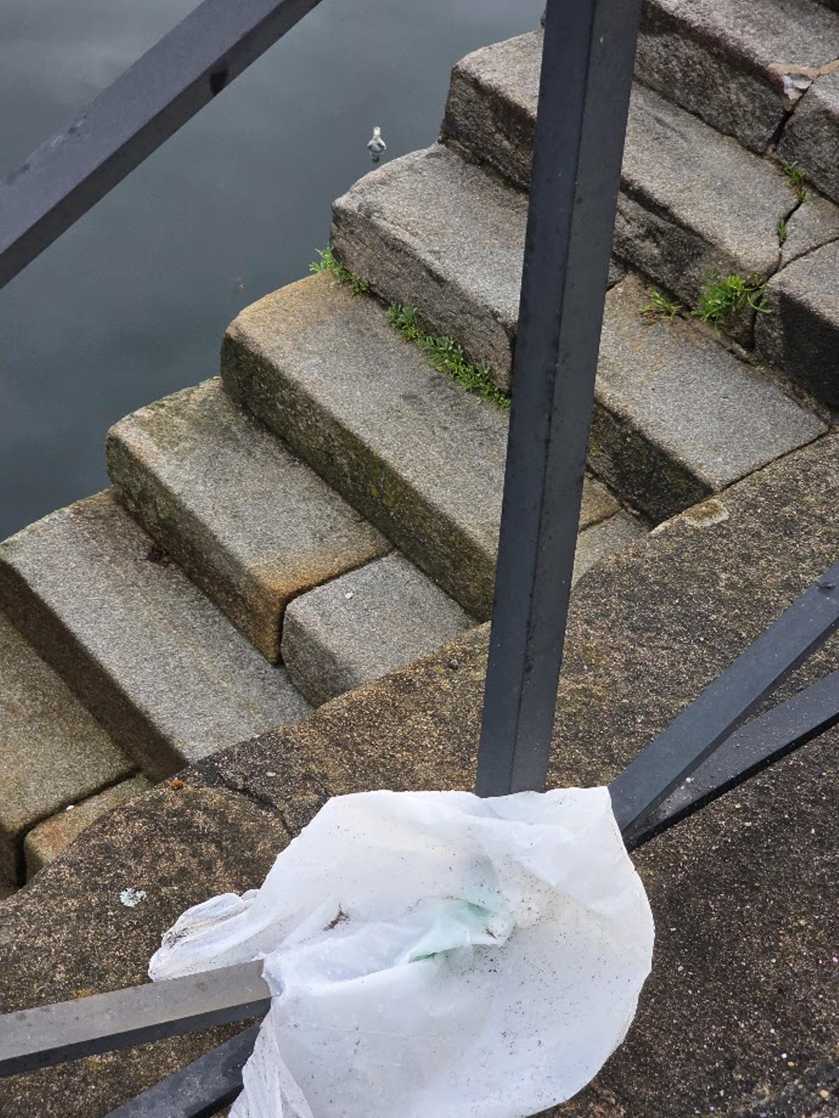 Una de las bolsas tiradas en el puerto y una de las botellas que flotan en la ría, esta mañana.