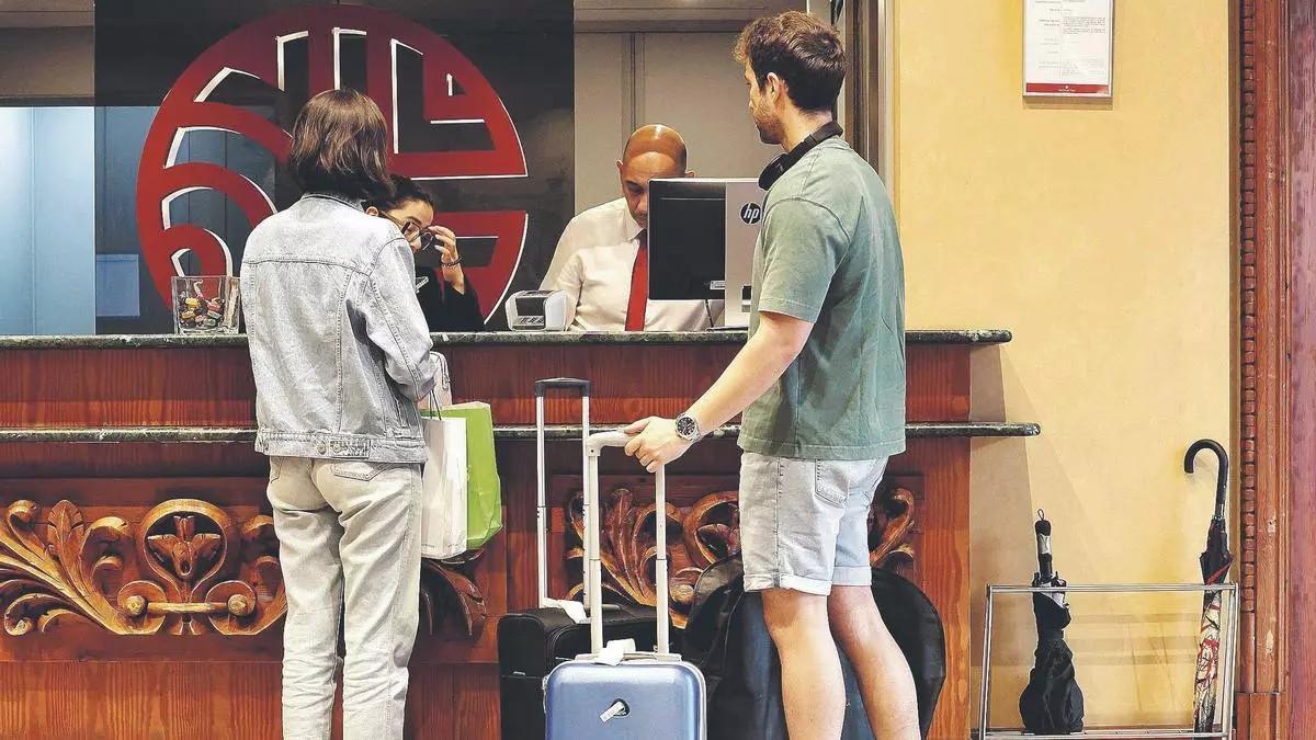 Dos turistas en la recepción de un hotel, en una imagen de archivo