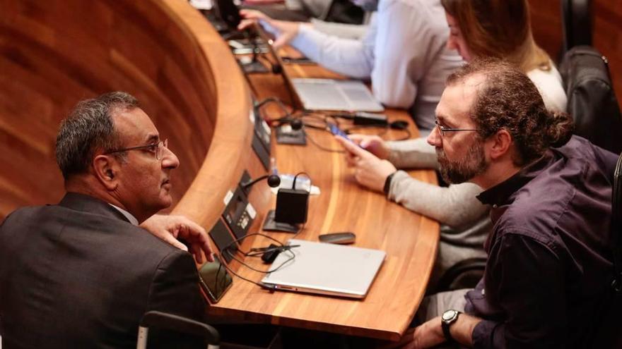 Fernando Lastra, a la izquierda, dialoga con el diputado de Podemos Emilio León, ayer, en la Junta.