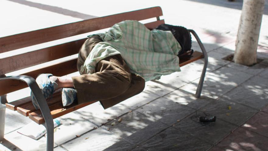Un indigente durmiendo en un banco