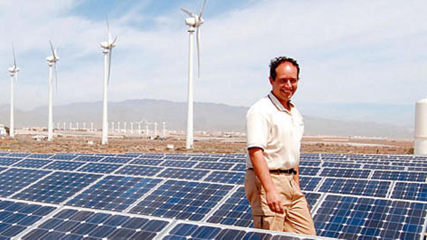 El encargado de la desaladora, José Manuel Díaz García, en medio de la planta fotovoltaica de Pozo Izquierdo, con generadores eólicos de la zona baja de Santa Lucía al fondo.   YAIZA SOCORRO