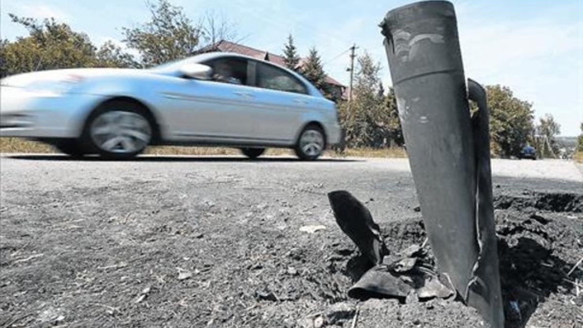 Un coche pasa junto a los restos de un proyectil en los suburbios de la ciudad ucraniana de Donetsk, ayer.