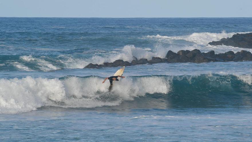 Un surfero cogiendo olas en la costa de Arucas.