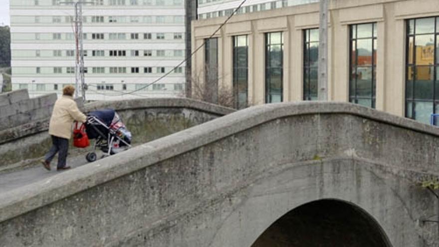 Una mujer atraviesa el puente sobre la vía del ferrocarril de A Sardiñeira.