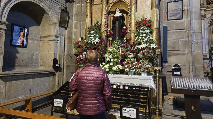 Una mujer reza ante la imagen de Santa Rita, con rosas en las manos y a sus pies, ayer.