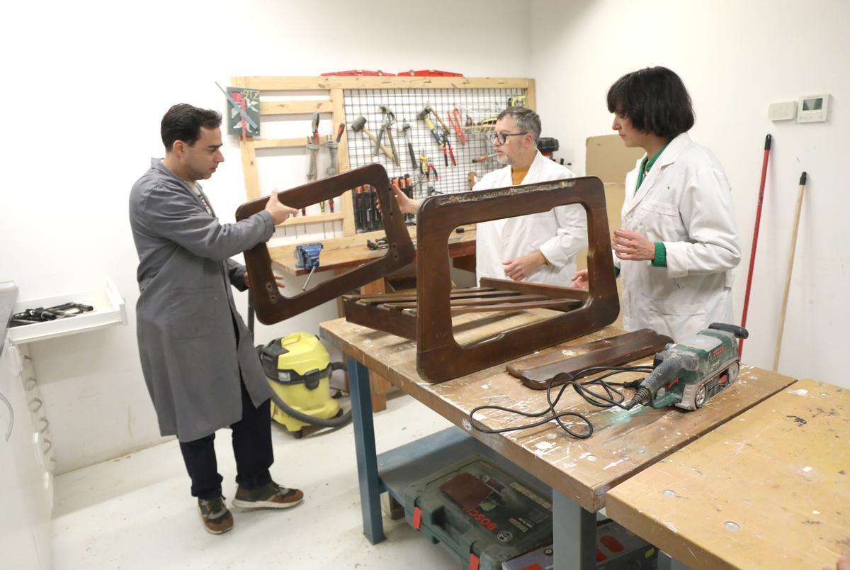 Roche, a la izquierda, ayuda a dos asistentes al taller abierto con un mueble que han llevado.