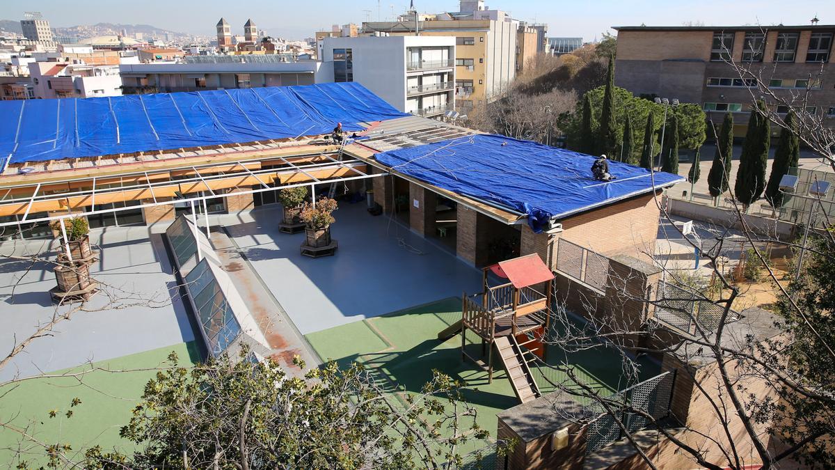 La lona desplegada en el tejado de la escuela Muntanyeta, en Barcelona, tras sufrir un robo y desprenderse parte del techo.