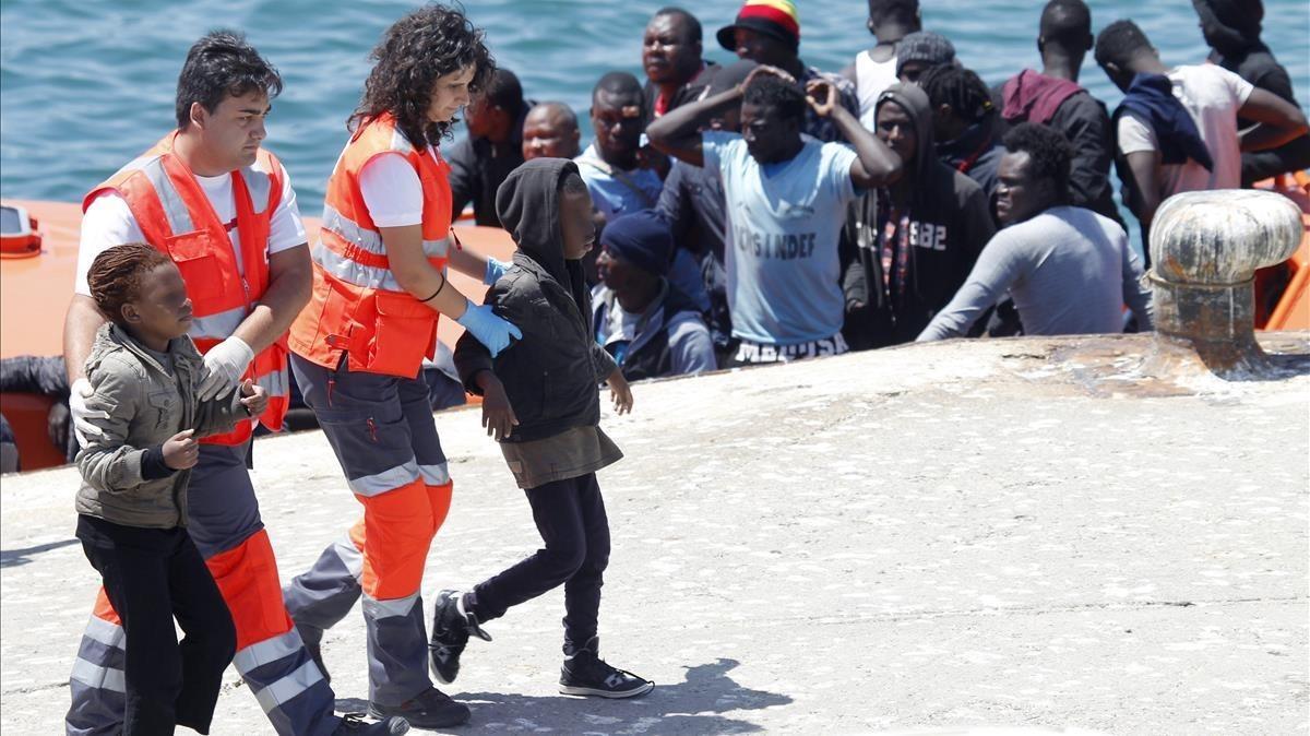 Dos menores acompañados por miembros de la Cruz Roja, a su llegada al puerto de Tarifa (Cádiz). 