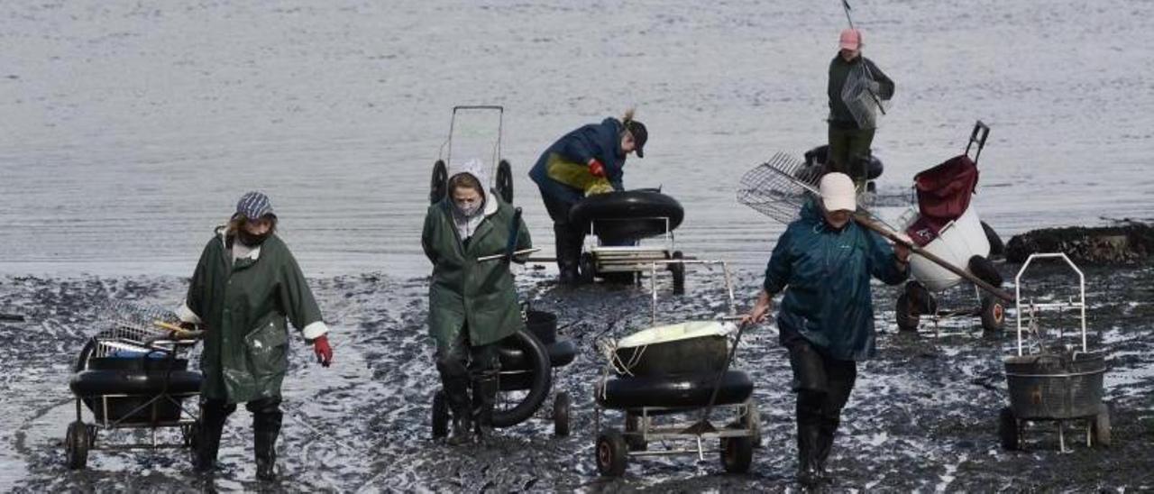 Las mariscadoras regresan ayer de los bancos en Placeres tras la jornada de trabajo. |   // RAFA VÁZQUEZ