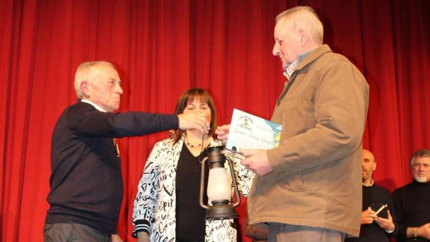 Laudino Suárez recibe un candil de manos de Enrique García, presidente vecinal del Regueral, ante la mirada de la alcaldesa, Amelia Fernández. | A. G.-O.