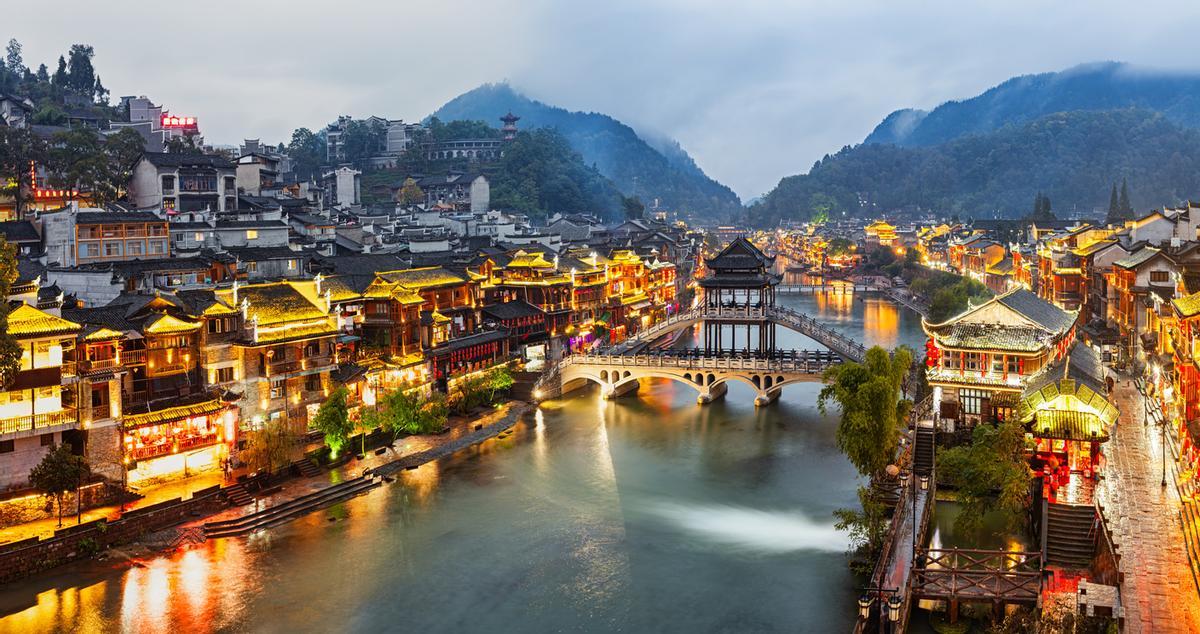 Al atardecer, el cielo de Fenghuang e tiñe de tonos rojizos y, a medida que oscurece, sus tradicionales casas de madera sobre pilotes encienden sus linternas rojas, creando un paisaje nocturno espectacular