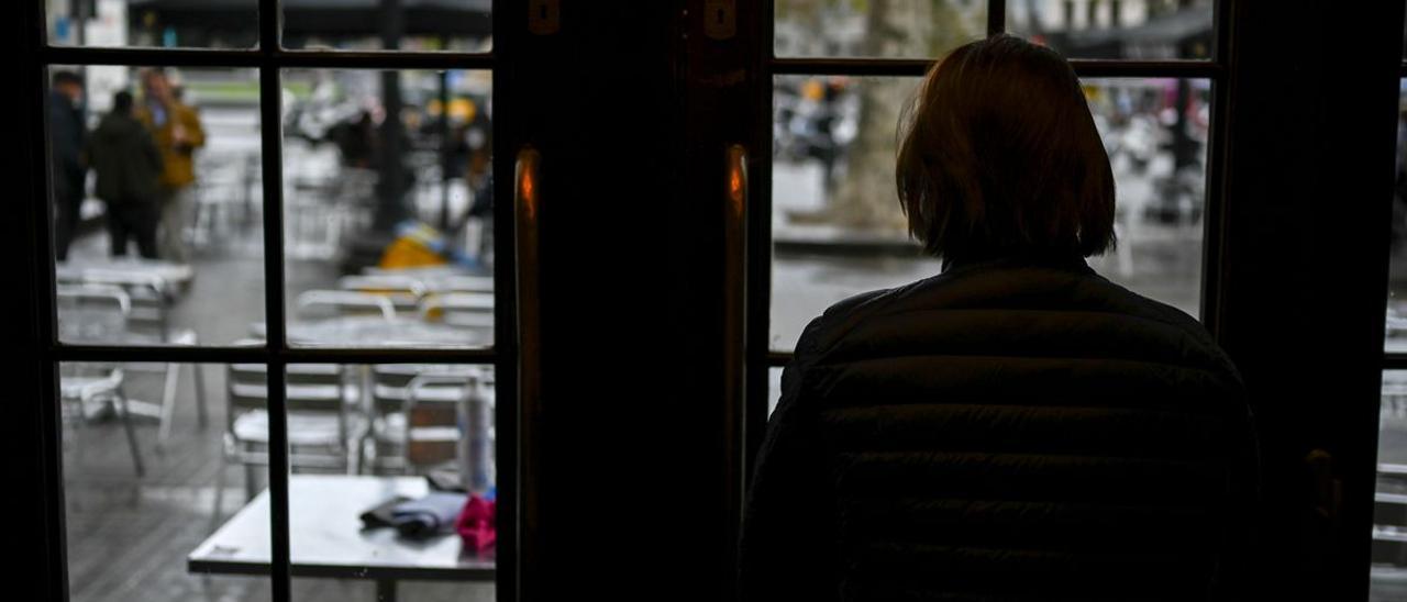 Irene mirando a través de una ventana del café Zurich de Barcelona.