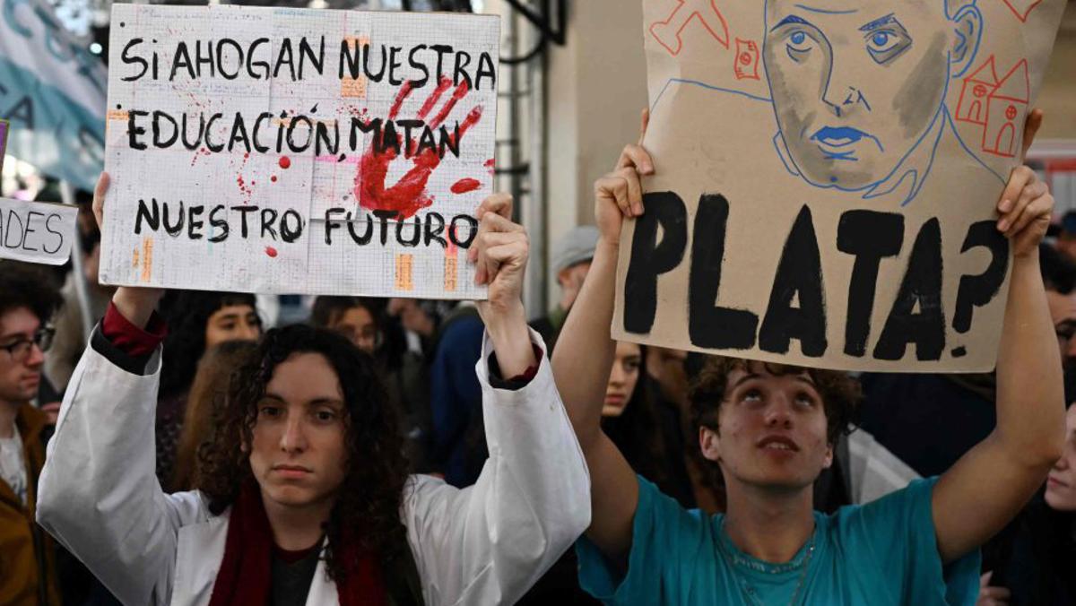 Dos estudiants sostenen cartells de protesta a Buenos Aires. | LUIS ROBAYO / AFP