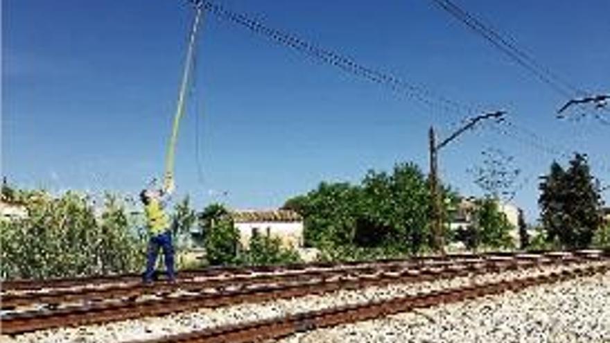 Un operari treballant per retirar el cablejat malmès de la via.