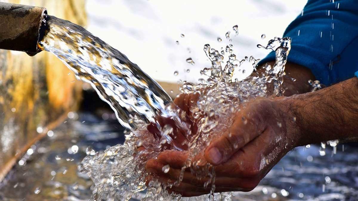 Un hombre se refresca las manos en una fuente