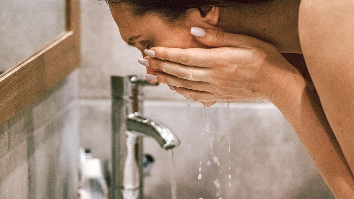 Una mujer se lava la cara.