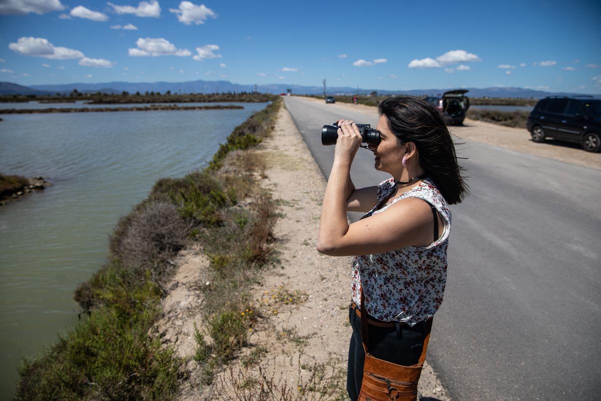 Una mujer observa aves a través de unos prismáticos en el delta del Ebro.