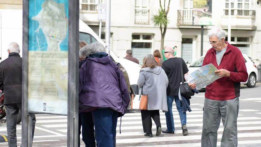 Turistas comprobando planos y señalizaciones en Gijón.