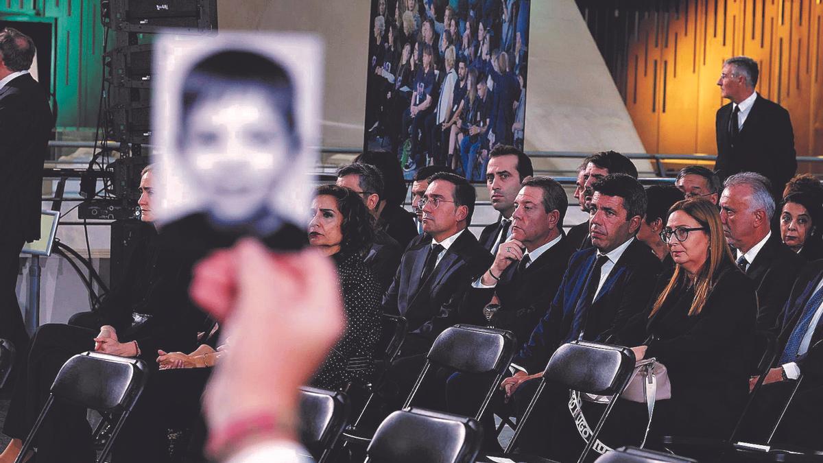 Un familiar muestra la foto de una víctima anta Mazón durante el funeral de Estado.
