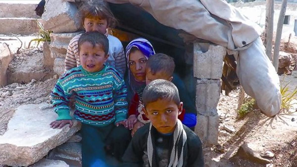 Fatima y su familia posan ante la boca de su refugio en Kafersijneh.