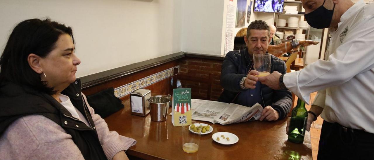 Dos clientes disfrutan de un culín en la sidrería Alberto y Marín Yarlequé, de la sidrería La Pámpana, con una caja de sidra Cabañón. | Á. G.