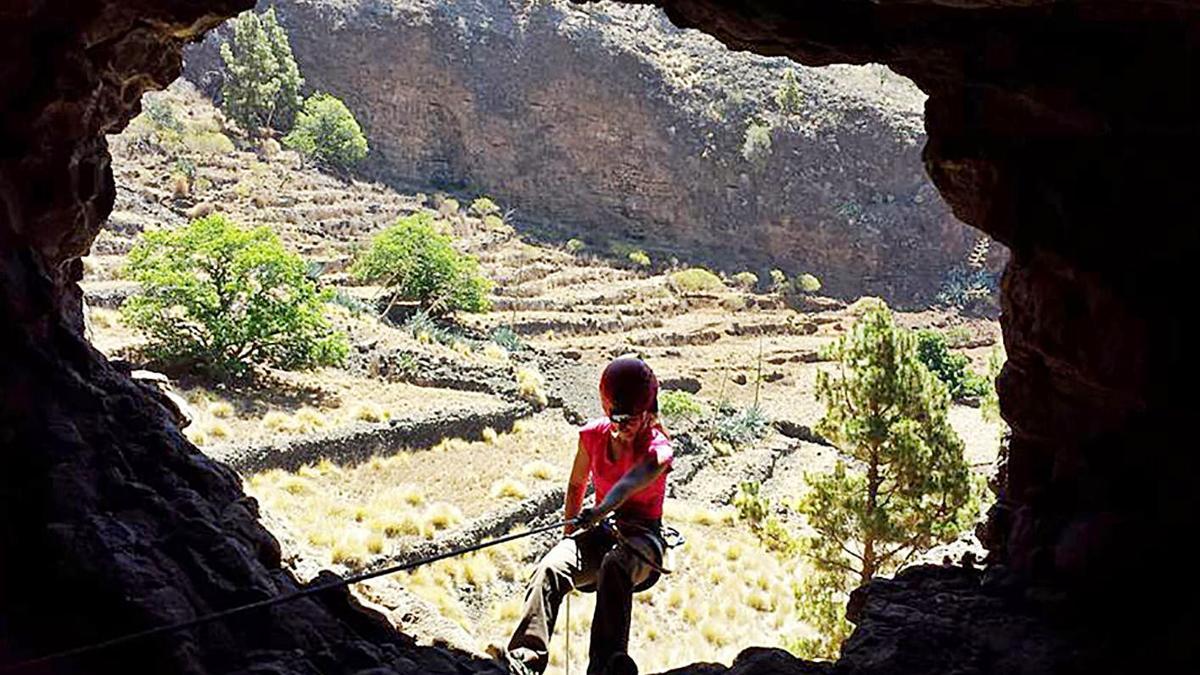 Una persona se descuelga desde el interior de una cueva a una pared exterior. | | E.D.