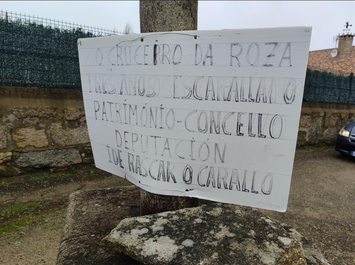 El cartel de protesta colocado por los vecinos en la base del cruceiro de a Roza.