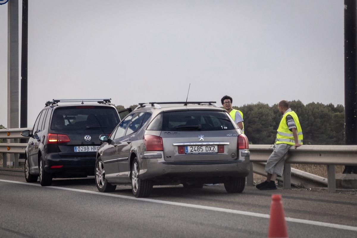 Varias personas esperando en el arcén, tras averiarse su coche, este martes.