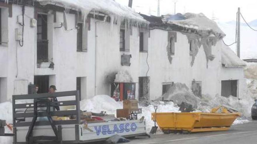 Los propietarios sacan enseres del edificio, con la parte del bar, quemada, en el centro.
