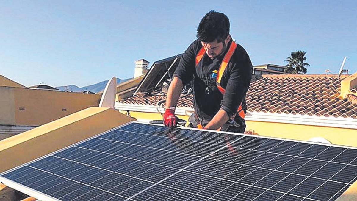 Un instalador coloca paneles solares en una vivienda.
