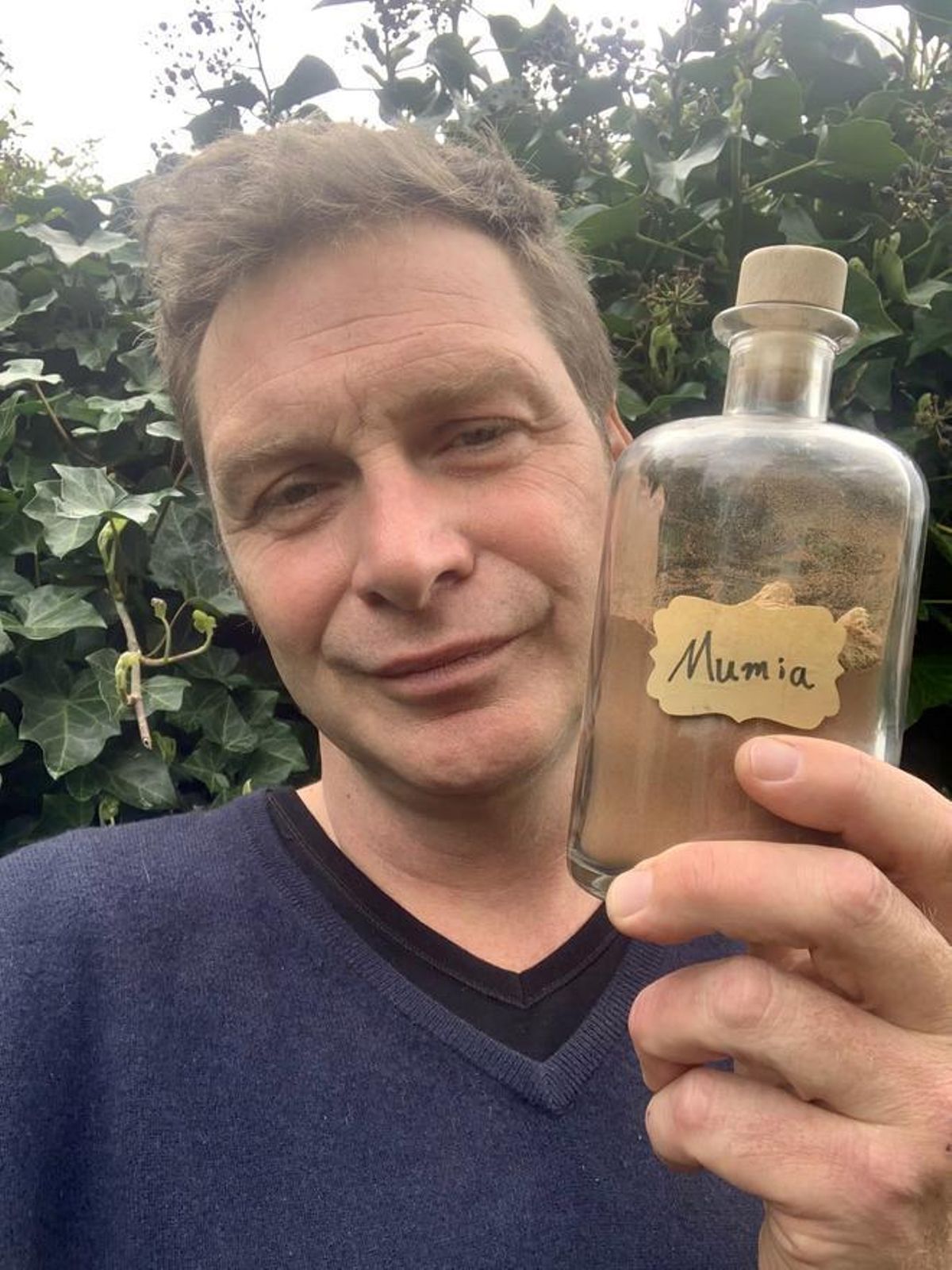 Oliver Pötzsch, sosteniendo un tarro de polvo de momias egipcias, que se vendía en farmacias europeas de finales del XIX y principios del XX.