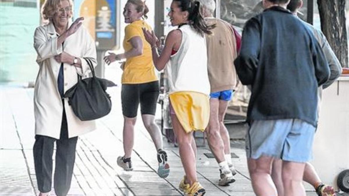 La alcaldesa de Madrid 8 Manuela Carmena es saludada en la calle por un grupo de corredores.