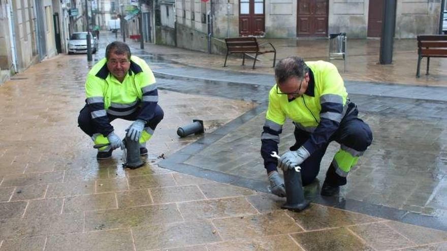 Dos operarios retiran los bolardos. // FdV