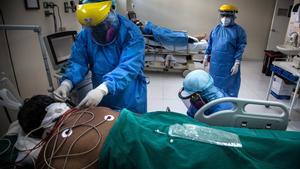 -FOTOGALERÍA- AME6947. LIMA (PERÙ), 01/05/2020.- Trabajadores de la salud atienden a un paciente contagiado con coronavirus ayer jueves, en la planta para el tratamiento de la Covid-19 del Hospital Sabogal de El Callao, en Lima (Perú). Con más de 1.000 muertos y cerca de 37.000 casos confirmados del Covid-19, Perú lucha sin tregua contra una enfermedad que amenaza con desbordar de forma inminente su endeble sistema sanitario. El Hospital Sabogal de la ciudad portuaria de El Callao es uno de los centros públicos de salud designados exclusivamente para la atención de pacientes contagiados con el virus. Allí, el equipo sanitario vela por sus pacientes desde la saturada sala de cuidados intensivos, donde la vida y la muerte penden de un estrecho hilo, hasta las más esperanzadoras salas de recuperación y observación, menos dramáticas pero que igualmente muestran los estragos causados por la enfermedad. Sabogal cuenta con tres plantas dedicadas en exclusiva al Covid-19, una de ellas solo par