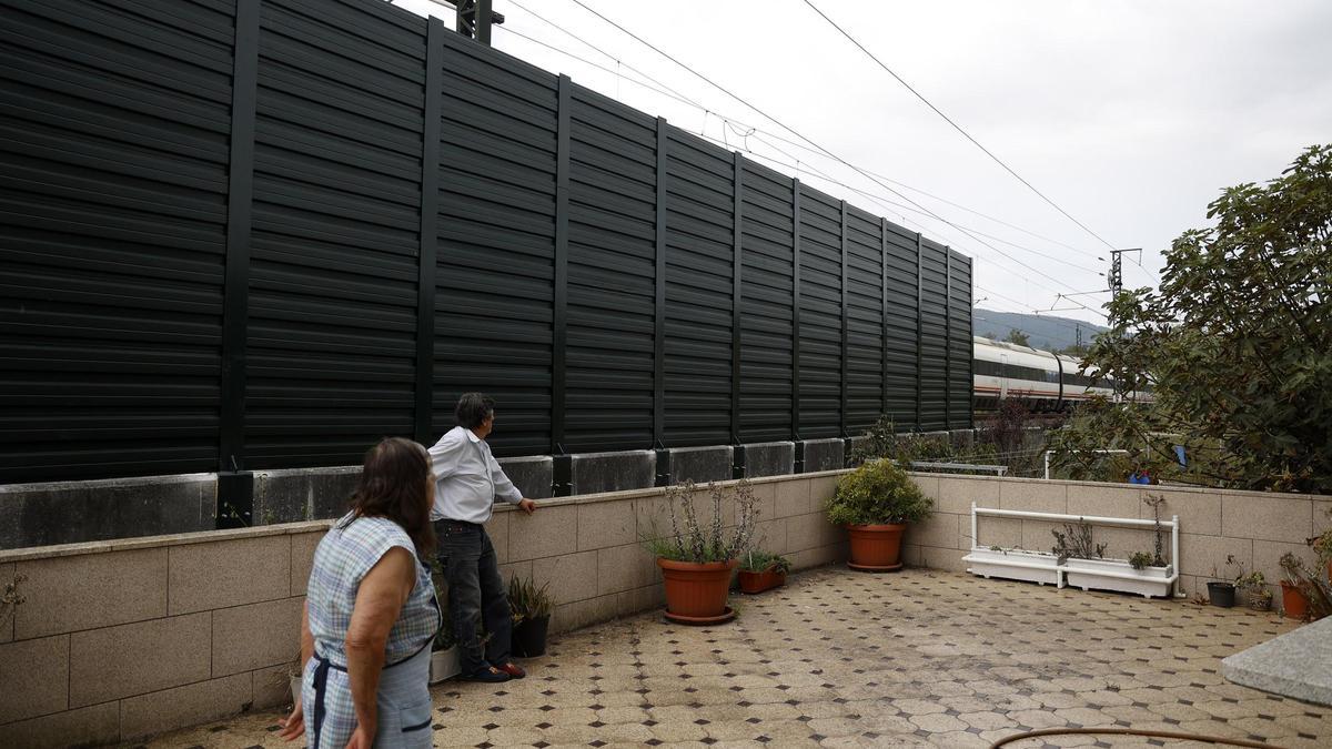 La familia en el patio de su casa con la pantalla ya instalada y un tren pasando.