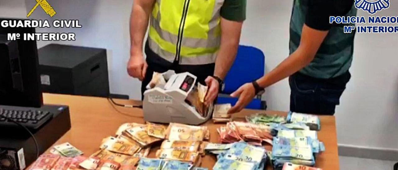 Dos agentes cuentan el dinero incautado a la red de narcos.