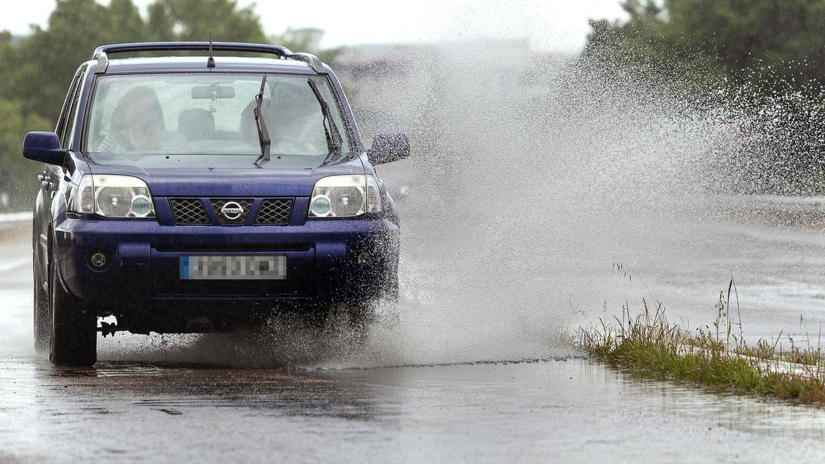 Un vehículo circula por una carretera afectada por la lluvia.
