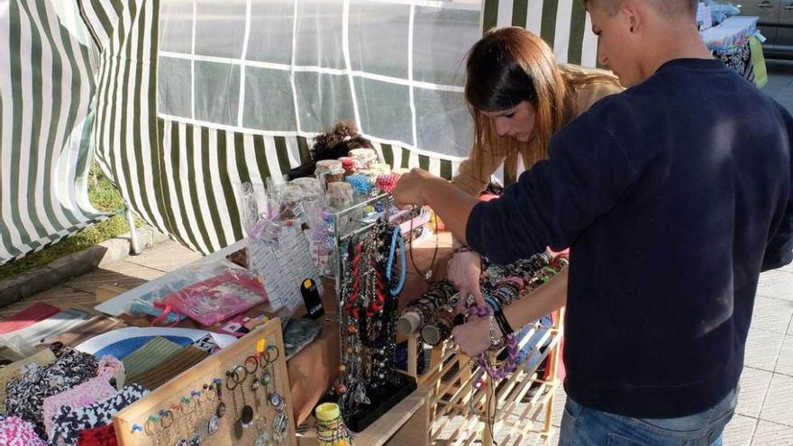 Dos jóvenes, en uno de los puestos del mercáu artesano.