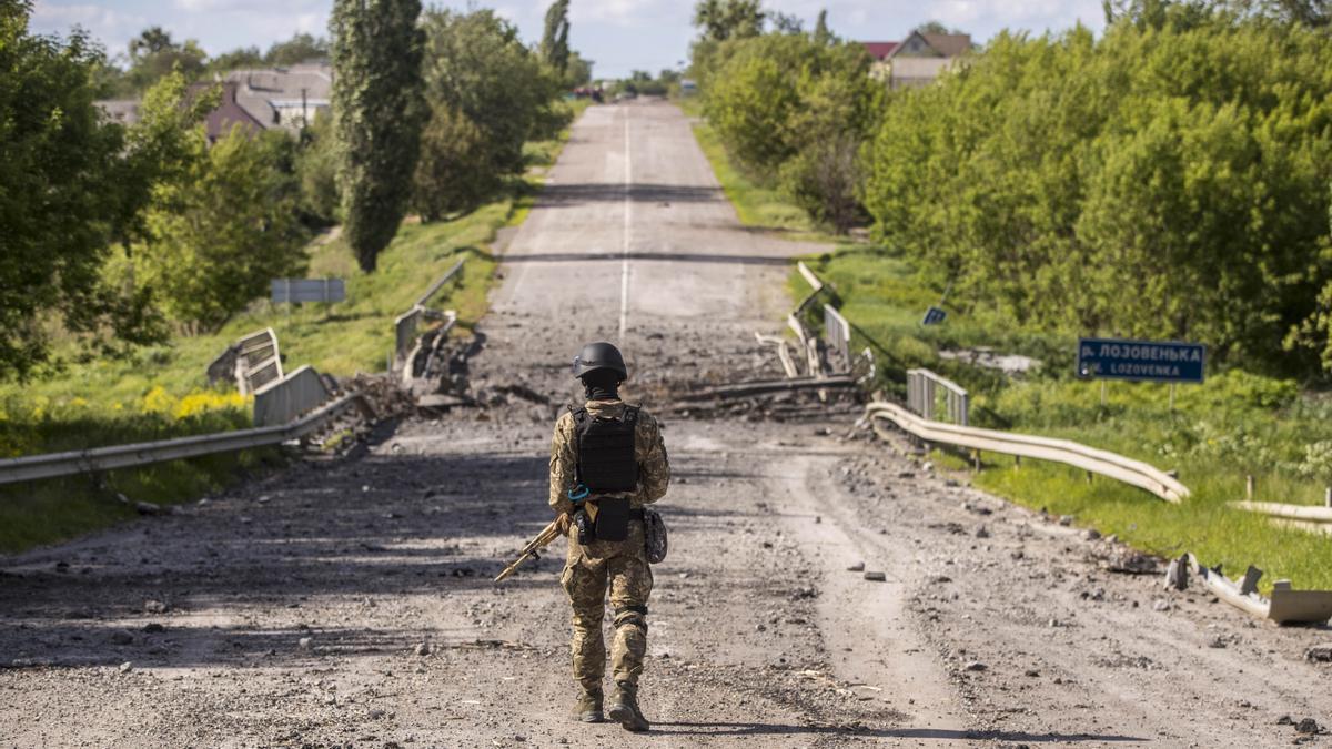 Un soldado patrulla una carretera de Járkov destruida por las bombas rusas.