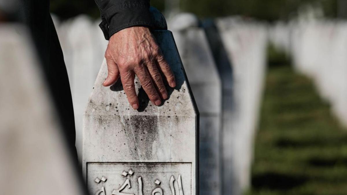 Un hombre toda una lápida en un cementerio musulmán.