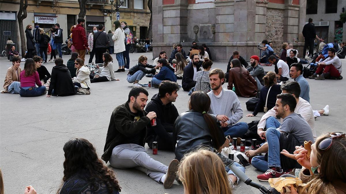 Grupos de jóvenes quedan para tomar algo en el suelo de la plaza de la Vila de Gràcia, en ausencia de bares y restaurantes por las tardes.