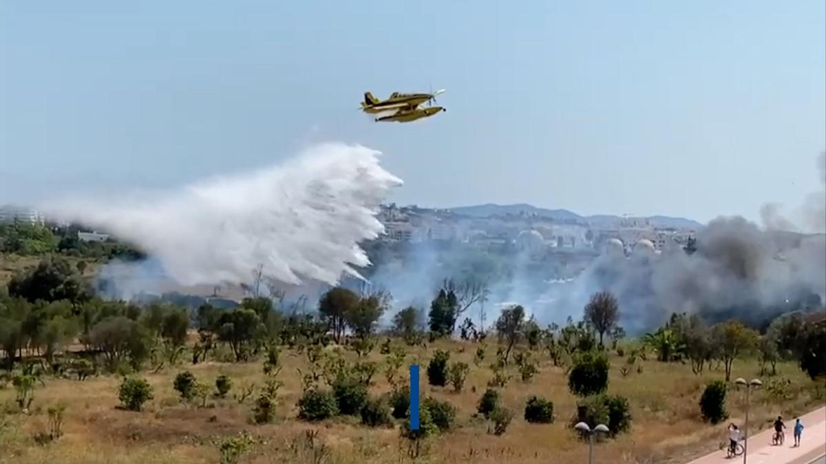 Una avioneta del Ibanat lanza una descarga de agua sobre el fuego