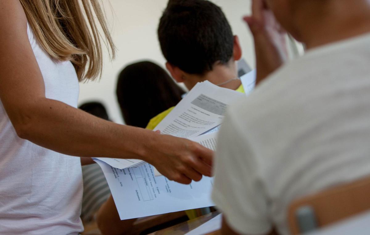 Una docente repartiendo exámenes en un centro educativo de Alicante