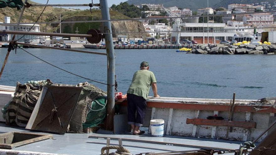 Un pescador mira per la borda al port de Llançà.