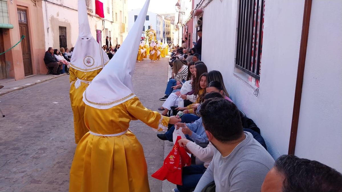 Un cofrade del Santo Cáliz obsequia a las espectadoras con dulces, una tradición propia de la Semana Santa alzireña.