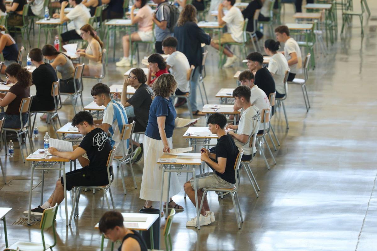 Una profesora reparte los exámenes de castellano entre los jóvenes.