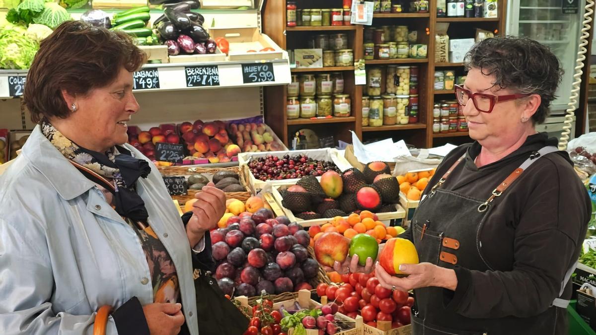 Ana Granda, con manzanas en la mano, y Mina Batalla en el puesto del mercado.