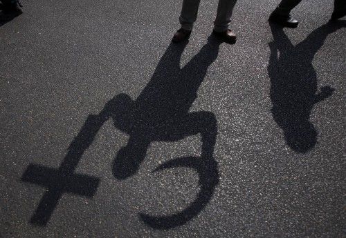 The shadows of a Cross and a Crescent are cast by an anti-Mursi and supporter of Egypt's army and police outside a police academy, where the trial of Mursi is due to take place, on the outskirts of Cairo