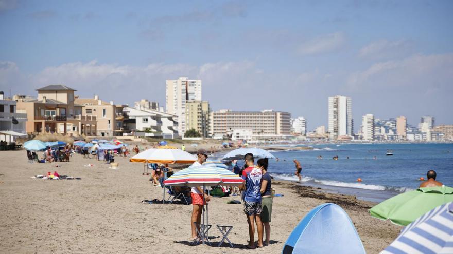 Bañistas en la playa de Levante de Cabo de Palos delante de unos edificios en una foto de archivo.