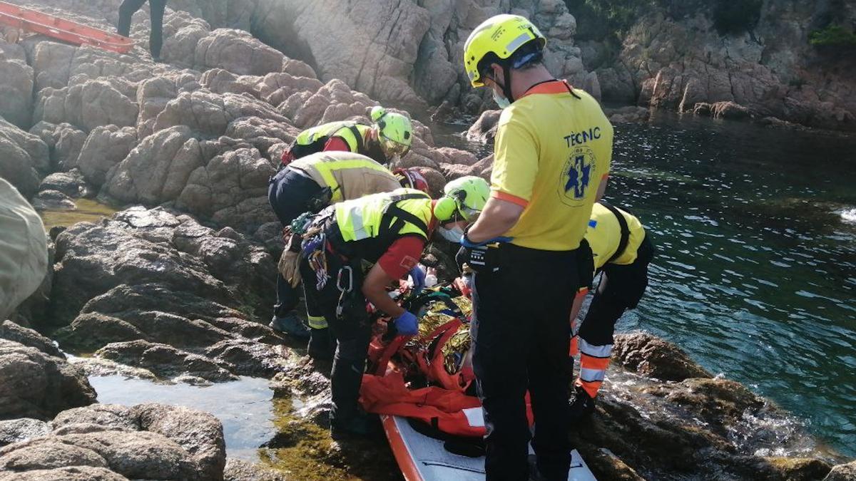 Bombers i personal del SEM rescatant una persona que navegava amb padle surf a Sant Feliu de Guíxols